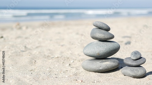 Rock balancing on ocean beach  stones stacking by sea water waves. Pyramid of pebbles on sandy shore. Stable pile or heap in soft focus with bokeh  close up. Zen balance  minimalism  harmony and peace