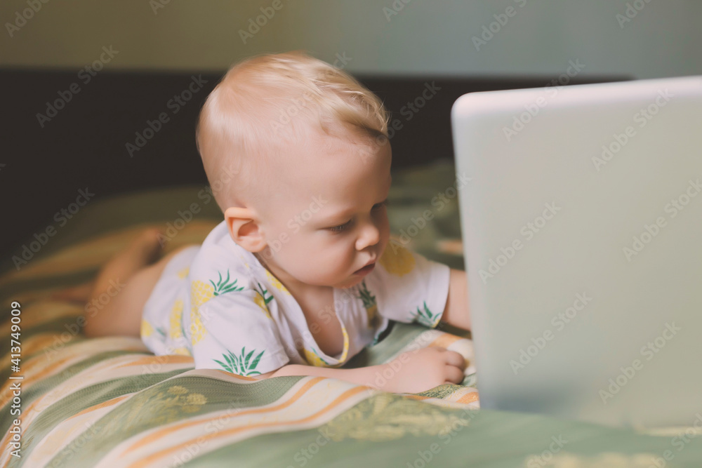 Cute baby boy with laptop computer lying on bed at home Cute baby boy with laptop computer lying on bed at home