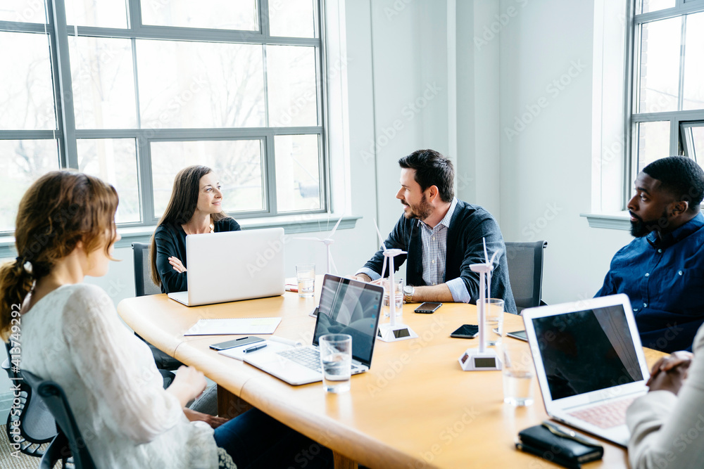 Business people discussing while sitting in board room at office Business people discussing while sitting in board room at office