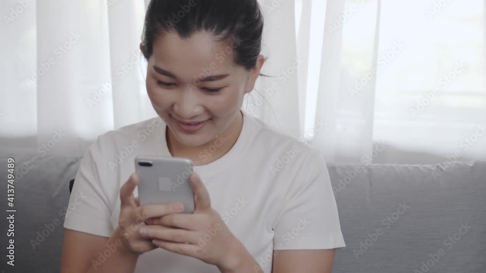 Close up Young Asian woman using a smartphone for shopping online by application E-commerce is easy to sell or buy everything sitting on the sofa in the living room at home Close up Young Asian woman using a smartphone for shopping online by application E-commerce is easy to sell or buy everything sitting on the sofa in the living room at home