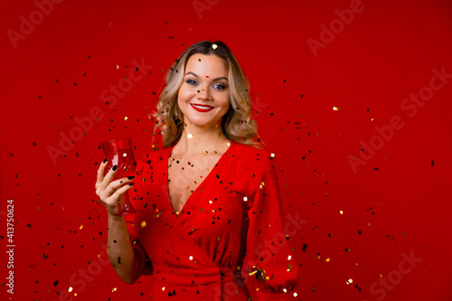 New year or holiday party, young blonde in red and gold confetti. © Alexander
