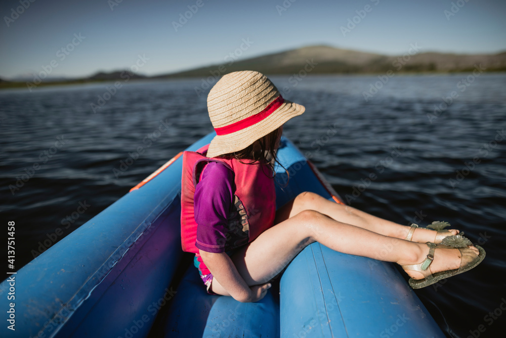 Side view of thoughtful girl wearing hat while sitting in inflatable raft on lake Side view of thoughtful girl wearing hat while sitting in inflatable raft on lake