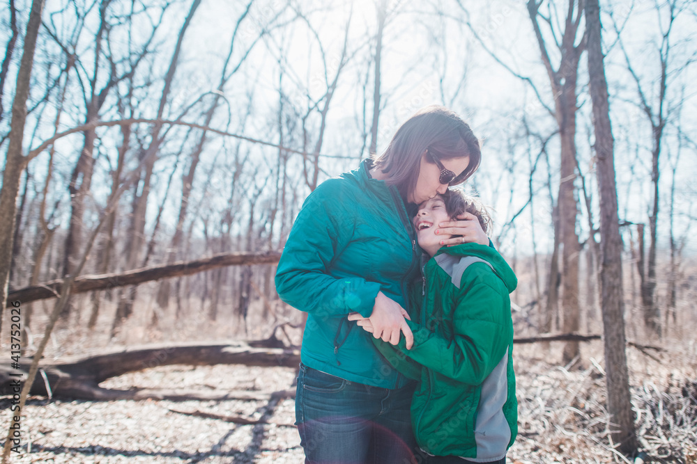 Mother embracing son while standing in forest Mother embracing son while standing in forest
