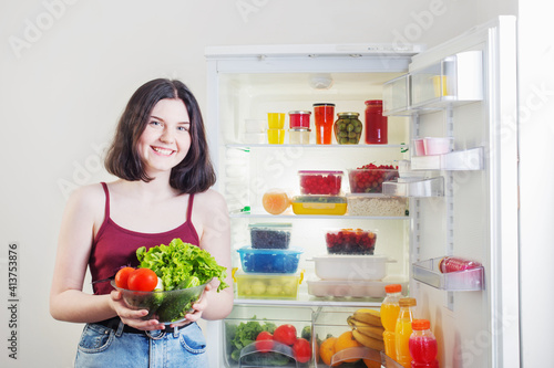 smile girl with vegetables near refrigerator with healthy food