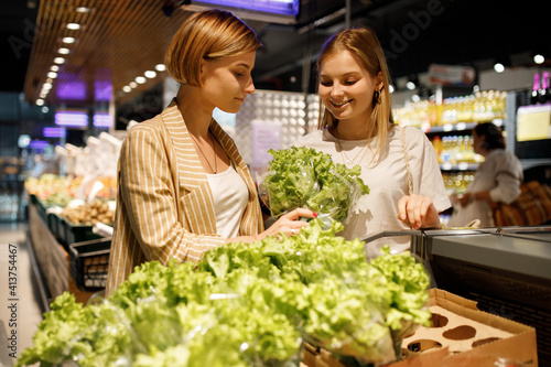 two young girl sisters are shopping at a supermarket beating fruits and vegetables. two young girl are shopping at a supermarket