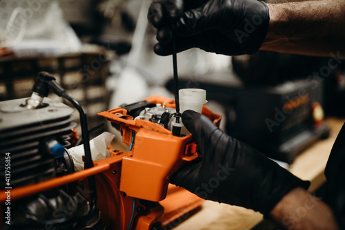 Man in workshop fixing chainsaw carburetor photo