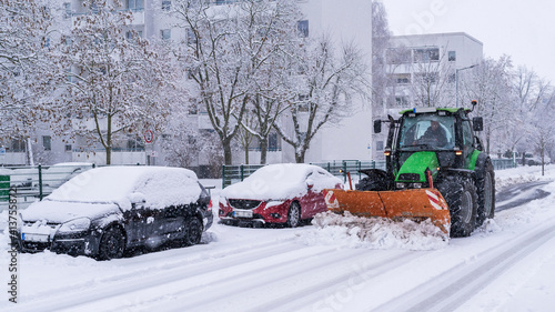 Ein Traktor mit Schneeflug räumt die Straßen in einer Stadt