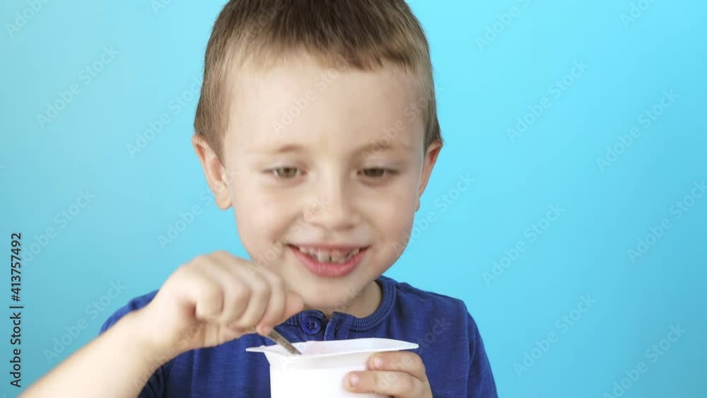 Little boy eatiing yogurt on blue background Little boy eatiing yogurt on blue background