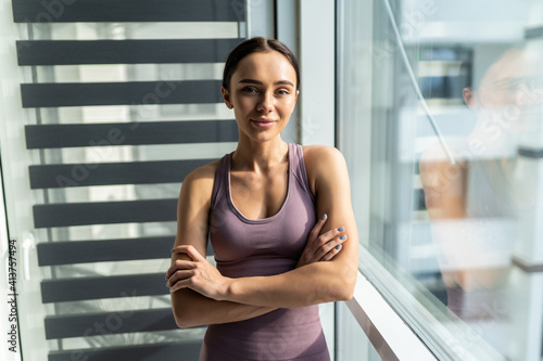 Beautiful fitness young woman while leaning on window at home