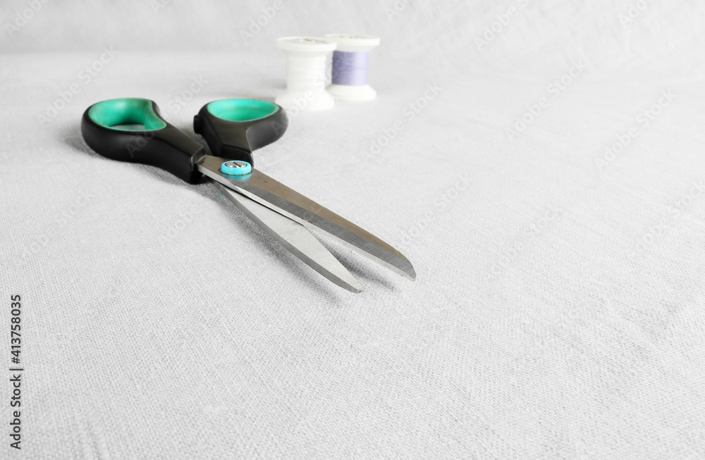 Scissors and thread on gray linen Scissors and thread on gray linen