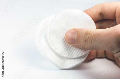 Man holding white cotton sponges on white background. Close up photo. Beauty, medicine and cosmetics procedures.