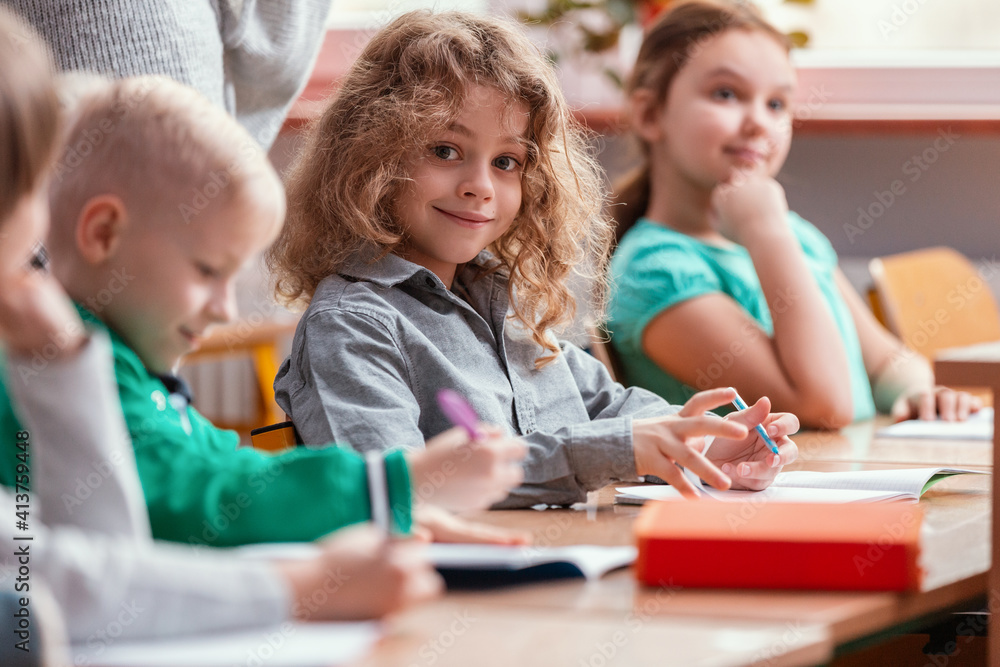 Children sit at the tables in the classroom waiting for the first lesson in the new school year Children sit at the tables in the classroom waiting for the first lesson in the new school year