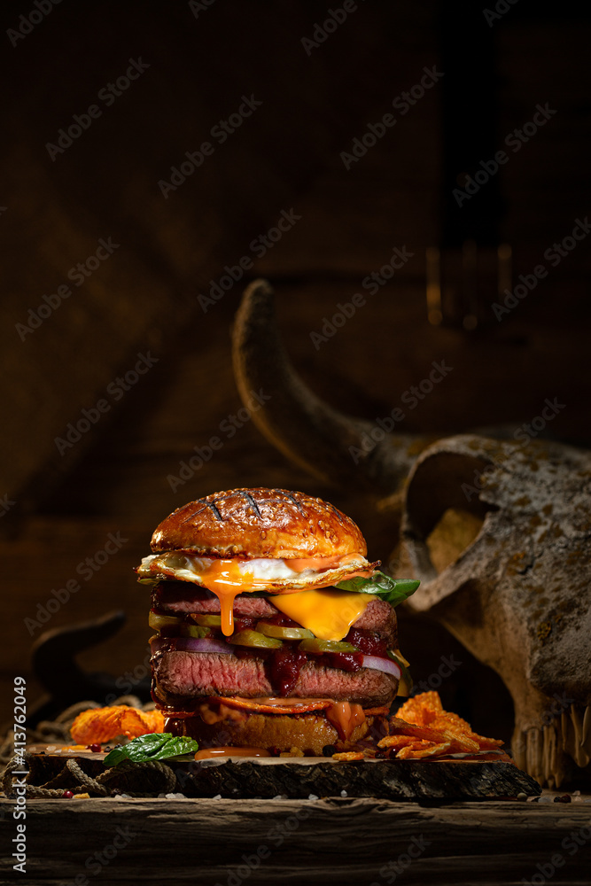 Rustic burger with beef steak, cheese and egg on dark background. Place for text