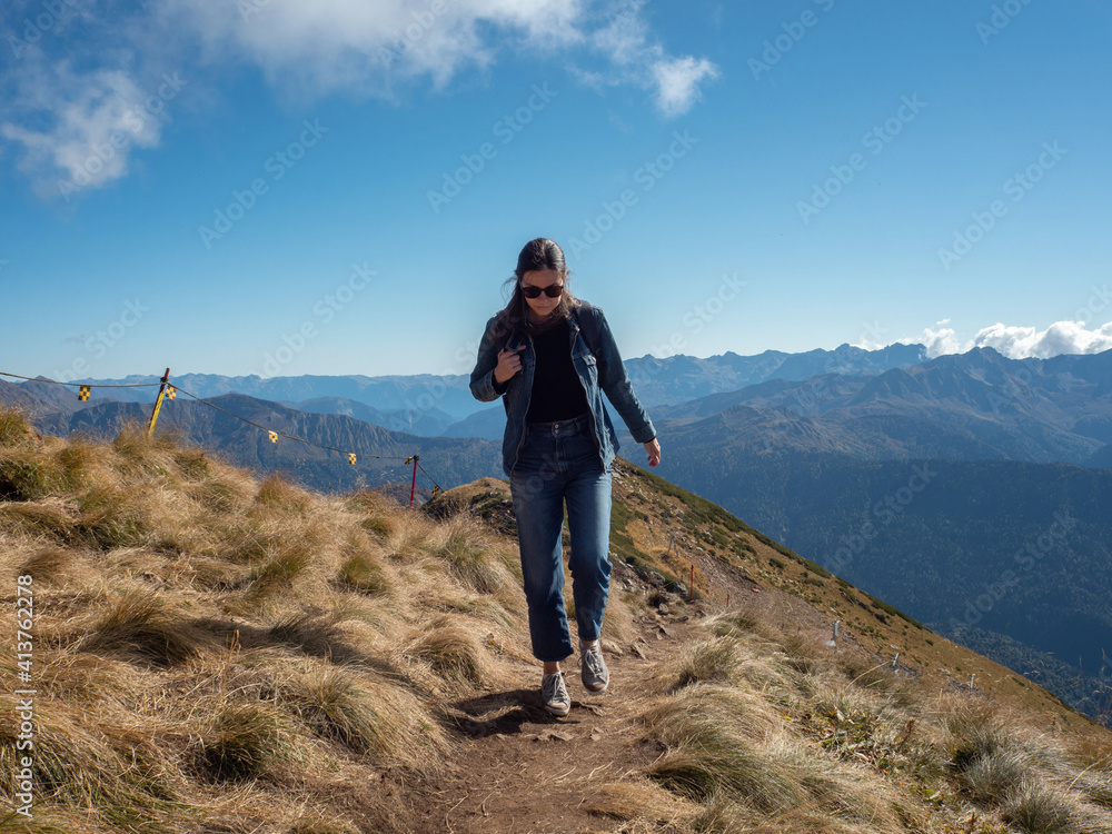 young female tourist with a backpack is walking in the mountains, traveling in national parks.