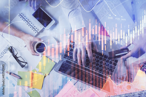 Multi exposure of man's hands typing over computer keyboard and forex graph hologram drawing. Top view. Financial markets concept.