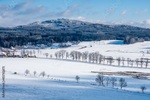 Winter hilly landscape scenery with snow, trees, houses in the Czech Republic