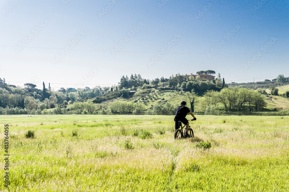 Rear view of young man riding mountain bike on grassy field against clear sky during sunny day Rear view of young man riding mountain bike on grassy field against clear sky during sunny day