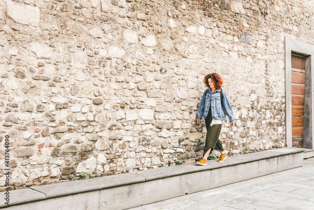 Woman walking on footpath by old building in city Woman walking on footpath by old building in city