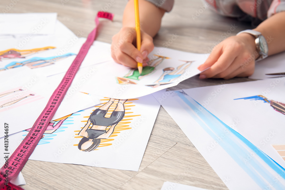 Female fashion designer working with sketches on floor in studio Female fashion designer working with sketches on floor in studio