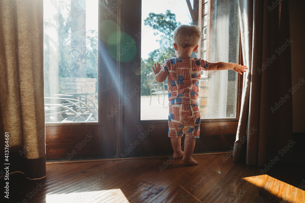 Rear view of baby boy looking through glass door at home Rear view of baby boy looking through glass door at home