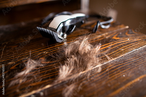 Side angle of freshly cut hair and clippers resting on a chair photo