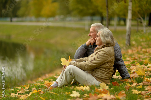 beautiful happy senior couple relaxing in park with autumn leaves