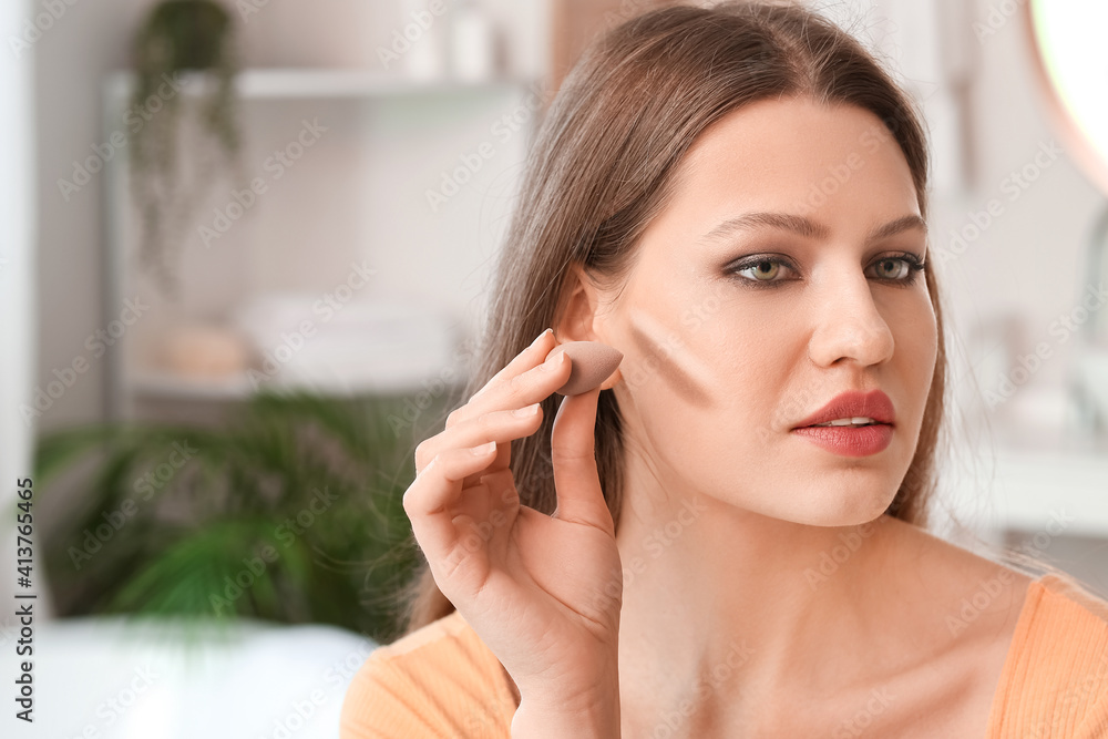 Beautiful young woman applying contouring makeup at home Beautiful young woman applying contouring makeup at home