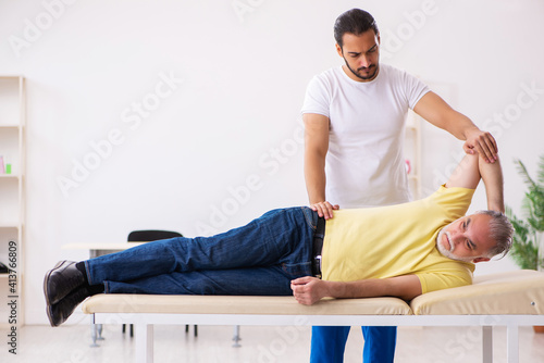 Old male patient visiting young male doctor chiropractor