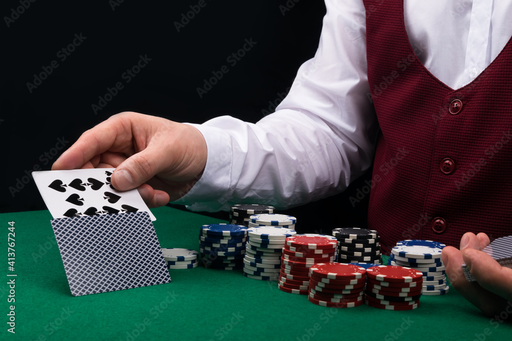 the croupier at the green poker table opens a combination of cards, close-up the croupier at the green poker table opens a combination of cards, close-up