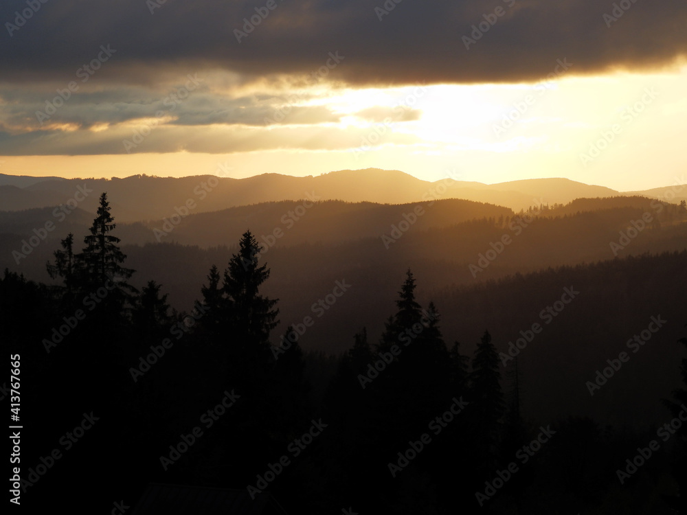 Beautiful summer sunset in the mountains with trees silhouettes