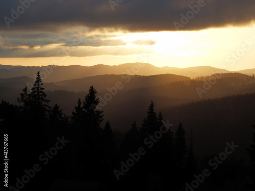 Beautiful summer sunset in the mountains with trees silhouettes