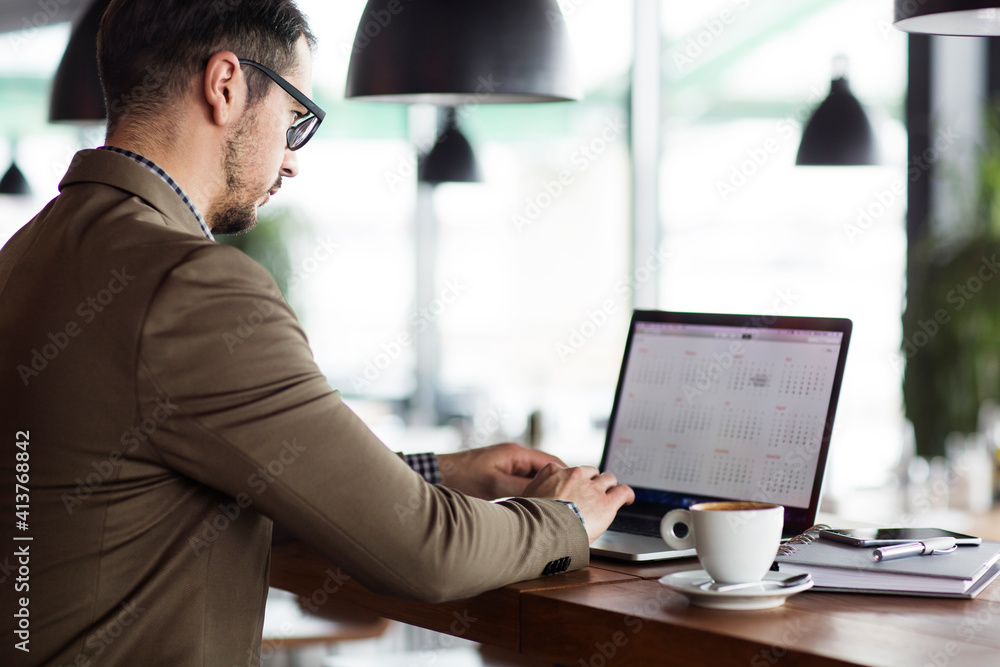 Businessman using laptop while sitting at table in cafe Businessman using laptop while sitting at table in cafe