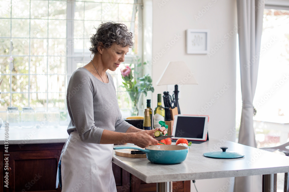 Mature woman chopping vegetables in kitchen Mature woman chopping vegetables in kitchen