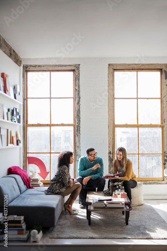 Businesswoman showing book on coworkers during discussing in office