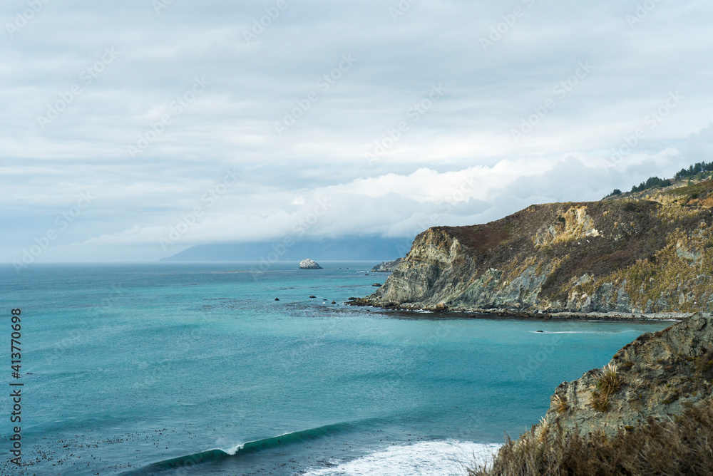 Scenic view of sea by mountains against cloudy sky Scenic view of sea by mountains against cloudy sky