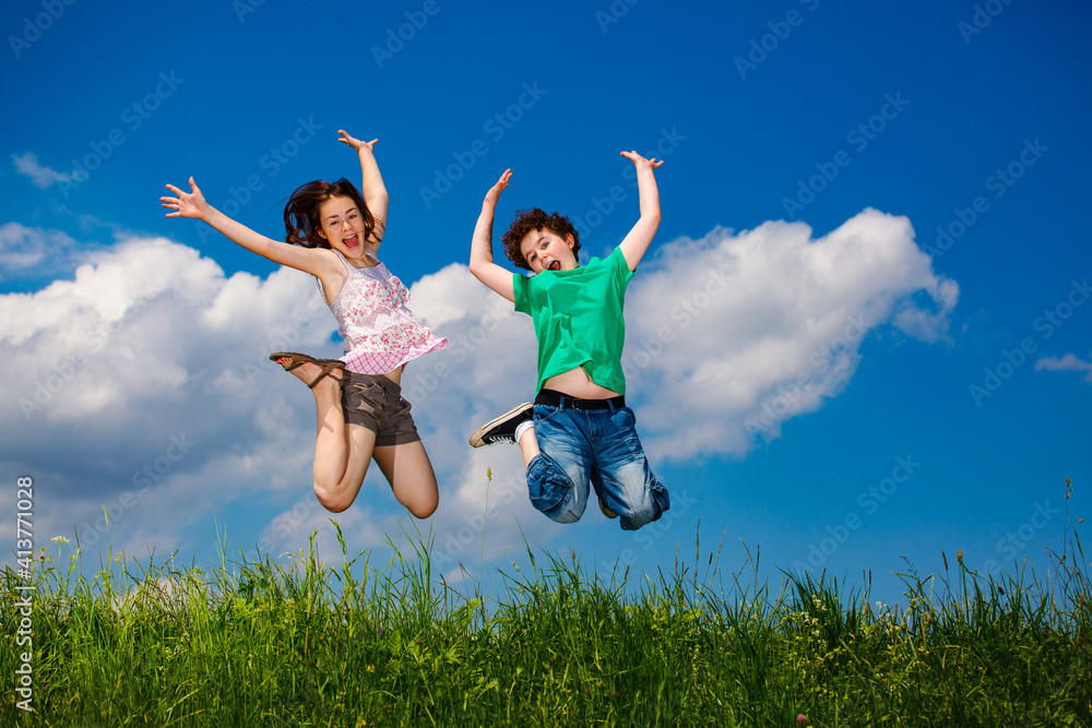 Girl and boy running, jumping against blue sky
Girl and boy running, jumping against blue sky