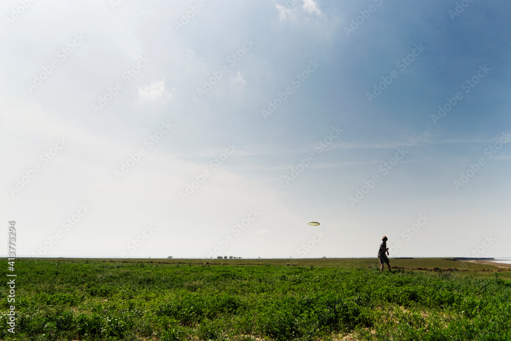 Man throwing flying disc on grassy field against sky Man throwing flying disc on grassy field against sky
