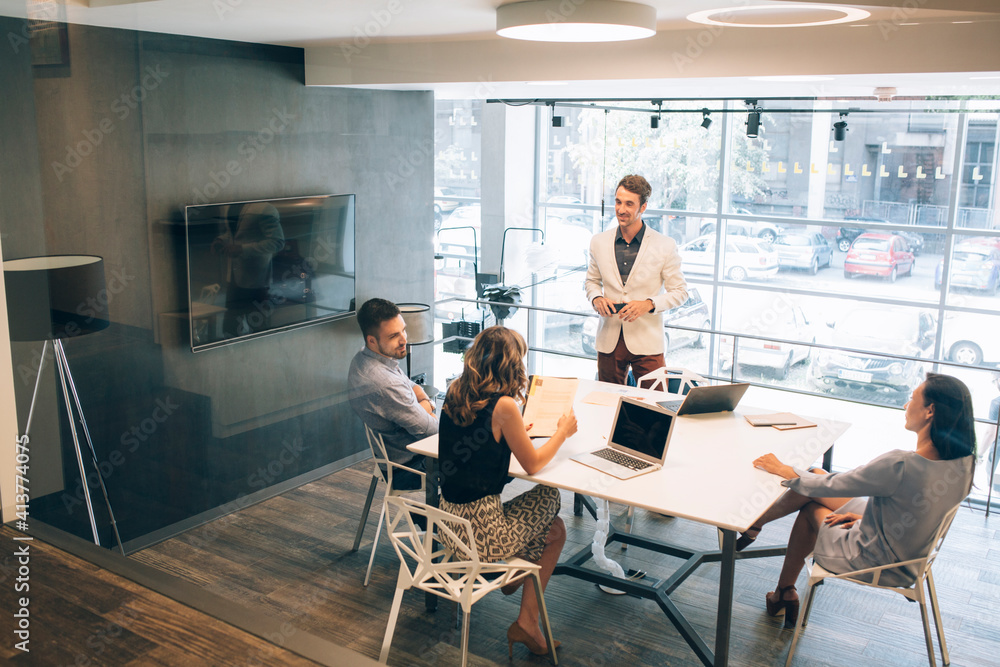 Business people discussing at desk in illuminated office Business people discussing at desk in illuminated office