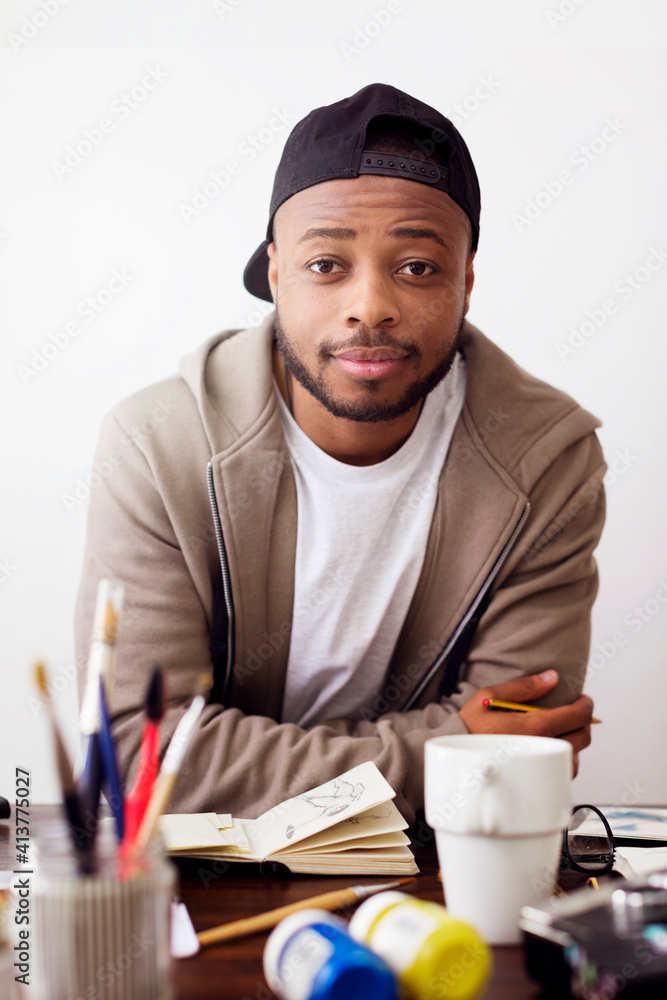 Portrait of confident painter sitting at desk in creative office Portrait of confident painter sitting at desk in creative office
