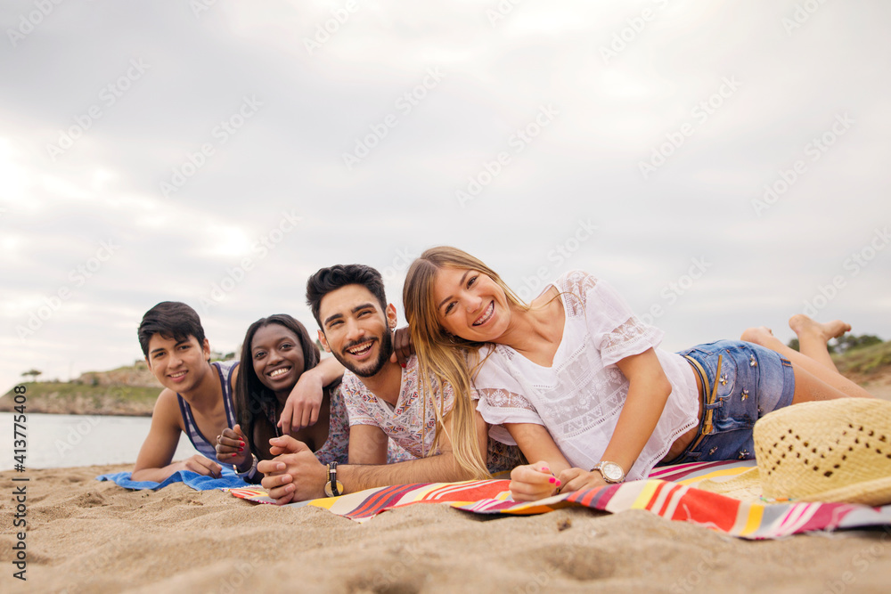 Portrait of cheerful friends lying on blanket at beach Portrait of cheerful friends lying on blanket at beach