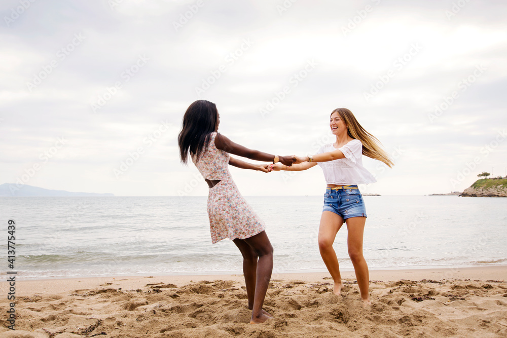 Cheerful female friends playing ring-around-the-rosy on beach Cheerful female friends playing ring-around-the-rosy on beach