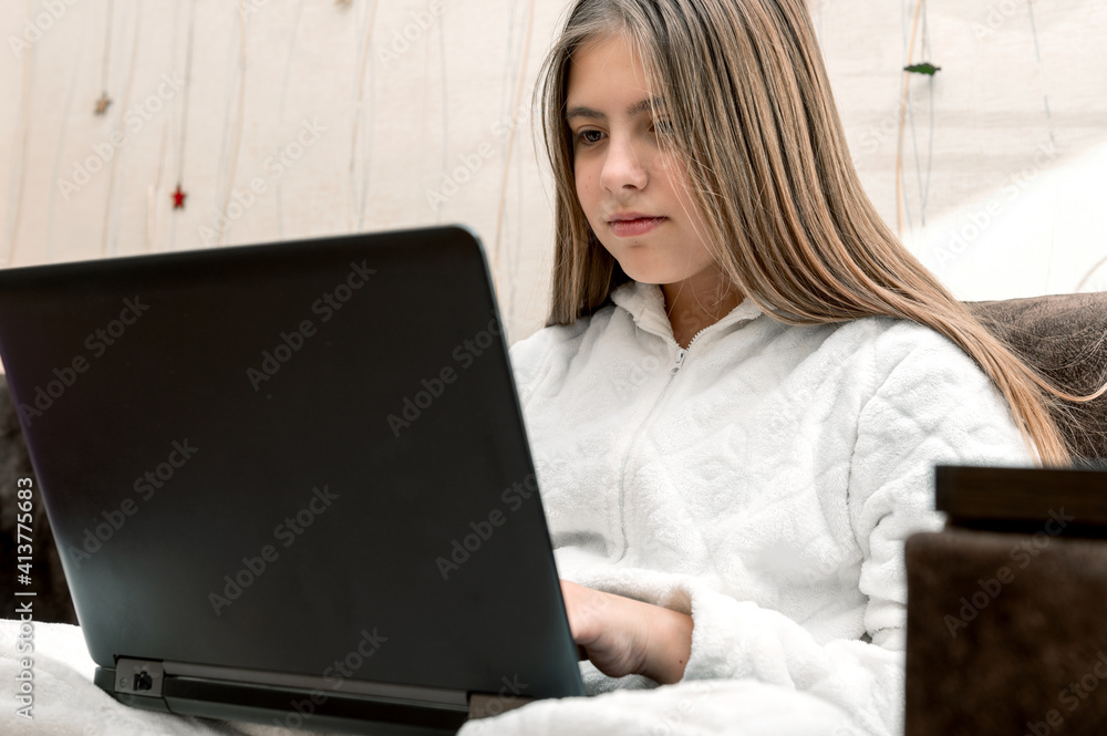 Teenager girl studying online at home looking at laptop. Online school. Home schooling. Teenager girl studying online at home looking at laptop. Online school. Home schooling.