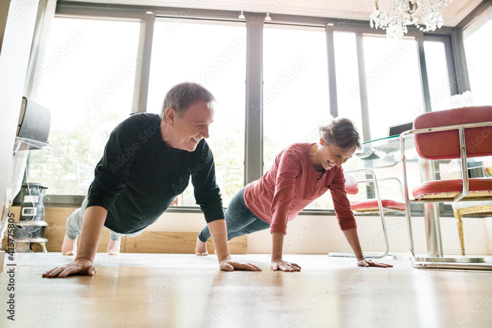 Happy senior couple doing push-ups at home Happy senior couple doing push-ups at home