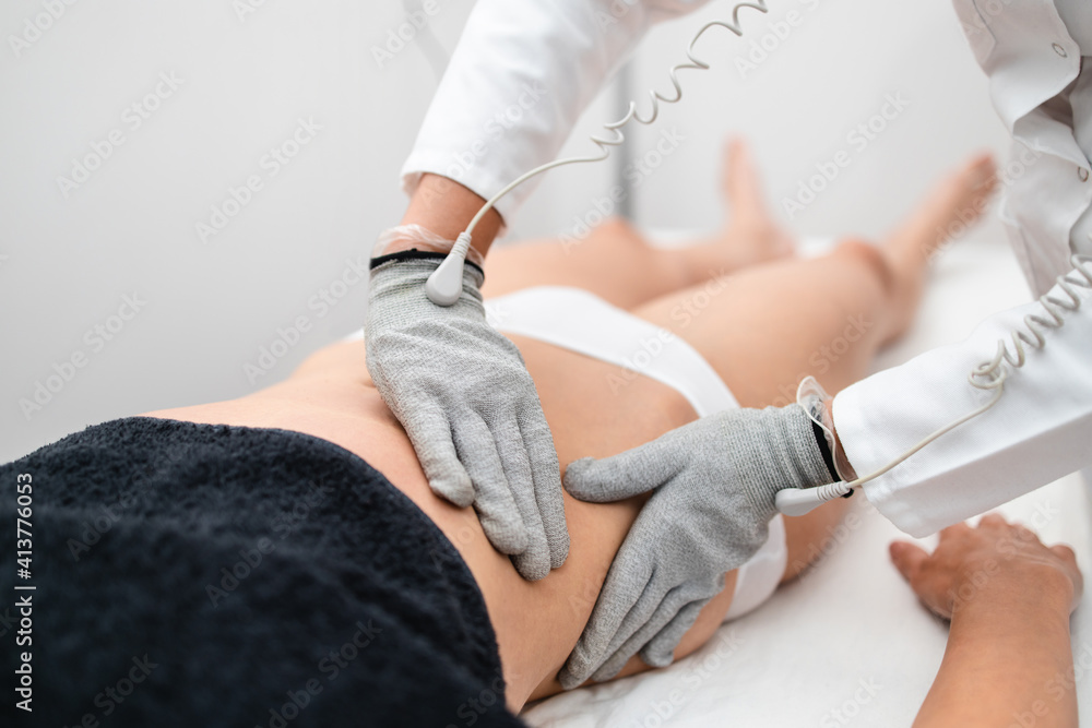 Fototapeta premium Micro sensory electrical BIO EMS micro-current treatment for face and body electrode stimulation with conductive gloves. Anti wrinkle and anti-aging lifting. Selective focus.