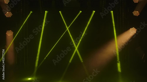 Bright yellow laser lights and spotlights revolve and move over dark stage. Shining empty stage for holiday show, awards ceremony or advertisement. Night laser show holograms. photo