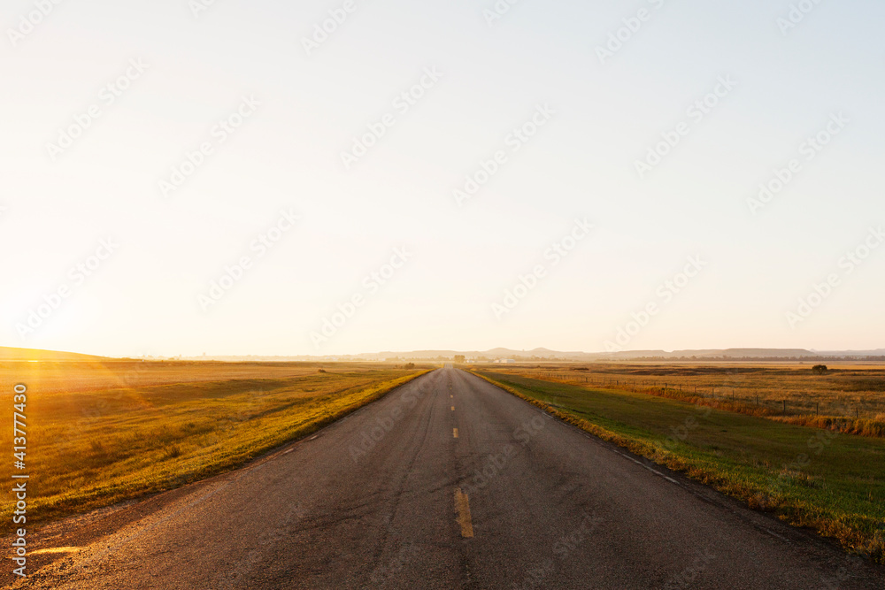 Highway amidst grassy field against clear sky during sunset Highway amidst grassy field against clear sky during sunset
