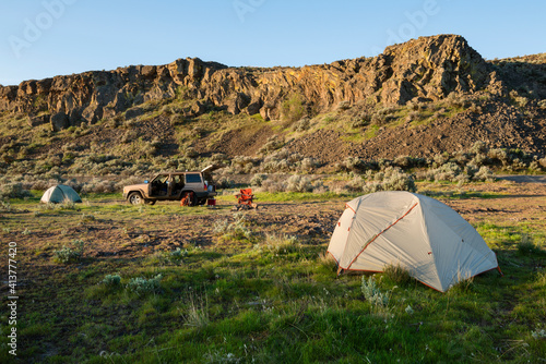 Tent on field by mountain at Gifford Pinchot National Forest with off-road vehicle in background photo