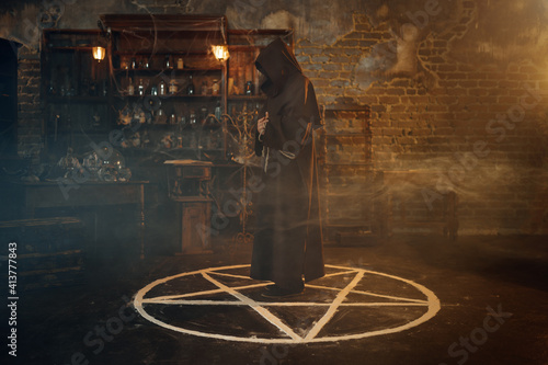 Photo Male exorcist in hood standing in the magic circle