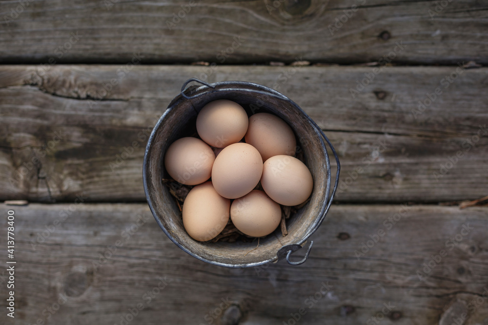 Overhead view of brown eggs in bucket on wooden table Overhead view of brown eggs in bucket on wooden table
