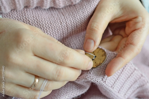 female workers' hands sew a wooden button to a jacket. close-up.